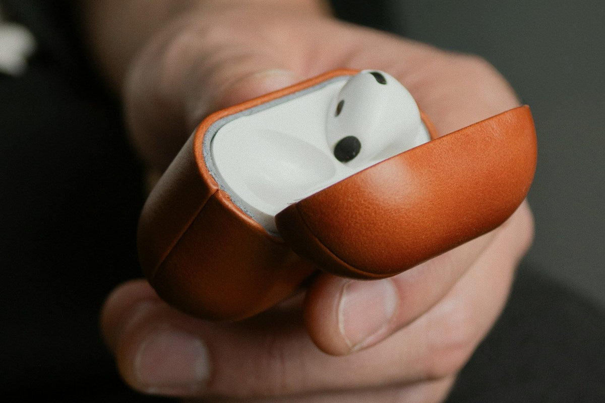 Saddle Brown full grain leather AirPods 5 case held open in a hand